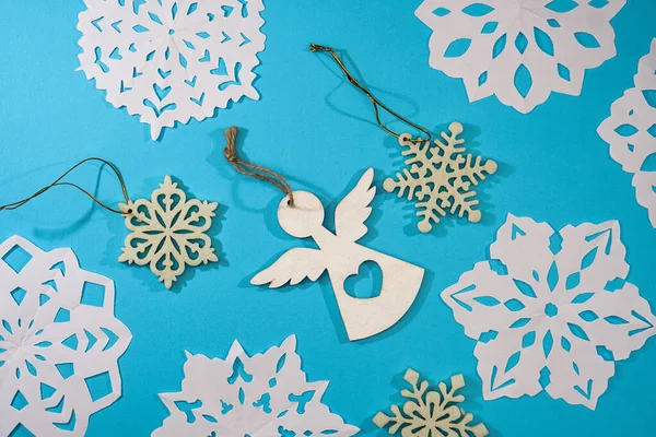Beautiful decorative snowflakes and little angel cut out of paper on a blue background. Photo for Christmas and New Year design