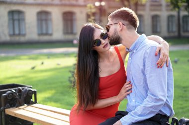Parktaki bankta oturan güzel bir çift adam ve kadın. Bir kız ve bir erkekle romantik bir tema. Bahar Yaz teması