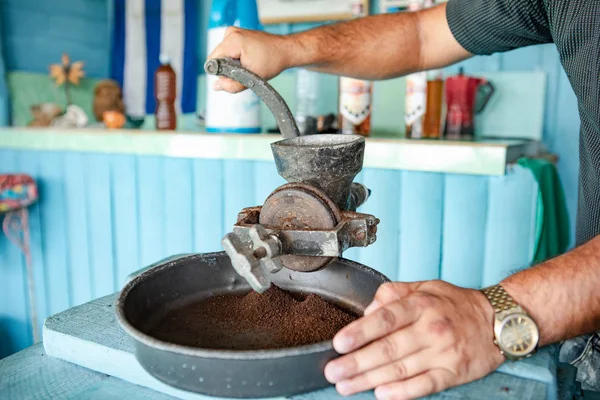 Cuba: Man grinds with an old coffee mill