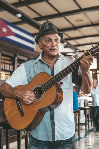 An old man with hat playing an acoustic guitar in a bar in Havan — Stock Photo, Image