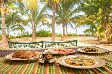 Breakfast on sea beach in Varadero/Cuba. Table setting with food and coffee in restaurant outdoor. Concept of travel and vacation in tropical resort. clipart