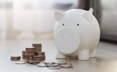 Beyaz domuzcuk ahşap zemin üzerinde para ile para tasarrufu.