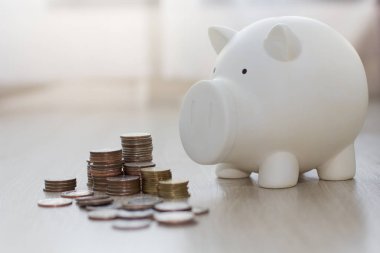 Beyaz domuzcuk ahşap zemin üzerinde para ile para tasarrufu.