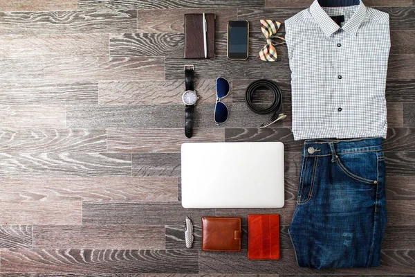 Set of casual men clothes and accessories on dark black wooden background. Top view.