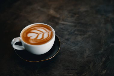 Kahve fincanı, eski masanın üstünde latte sanatı.