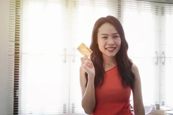 アジアの美しい若い女性の肖像画でオレンジベストでコピースペース彼女は陽気で手を握っているオンラインショッピングのためのクレジットカードデザイン — ストック写真