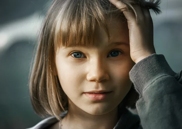 Triste adolescente chica con corto pelo rubio y ojos azules sobre fondo gris —  Fotos de Stock