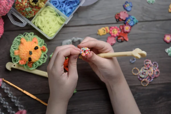 children's hands are weaving figures out of colored rubbers