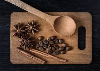 kahve, yıldız anason, tarçın, ahşap kesme tahta kaşık ve koyu arka plan