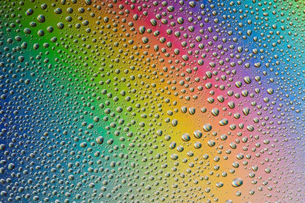 Misted glass, drops closeup on rainbow colored background — Stock Photo, Image