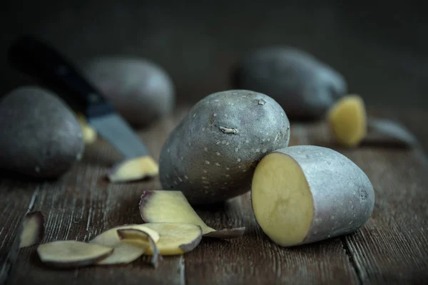 Frische Kartoffelknolle und schneiden Sie die Stücke mit einem Messer auf dem Holztisch im rustikalen Stil — Stockfoto