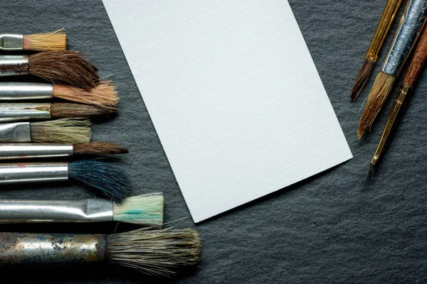Escova, pintar folha branca de papel sobre um fundo escuro — Fotografia de Stock