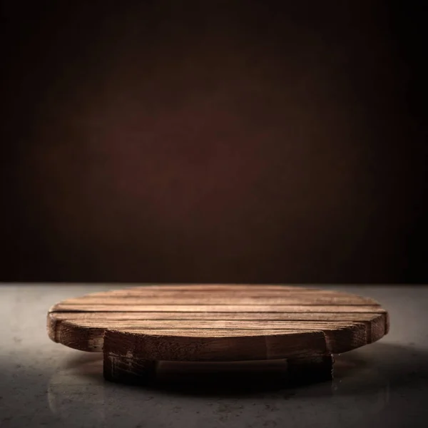 Soporte redondo de madera para la amargura de los alimentos sobre un fondo oscuro, lugar para la inscripción, cubierta — Foto de Stock