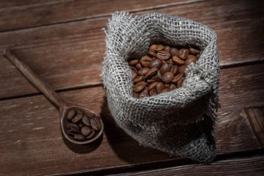 Kahve çekirdekleri kendir çuval ve bir kahverengi ahşap zemin üzerinde Kepçe