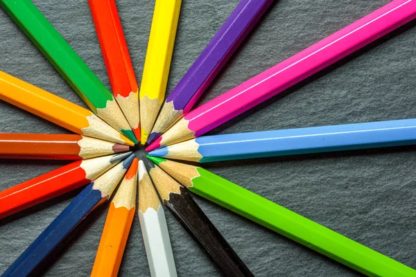 De nombreux crayons de couleur différents soigneusement pliés sur fond de table en bois — Photo