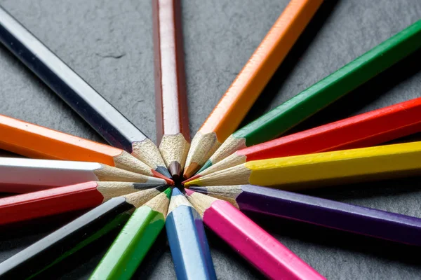 De nombreux crayons de couleur différents soigneusement pliés sur fond de table en bois — Photo