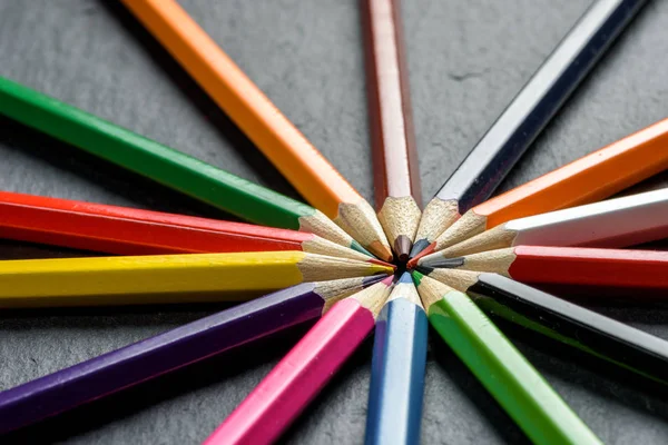 De nombreux crayons de couleur différents soigneusement pliés sur fond de table en bois — Photo