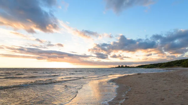 Quiet empty beach at sunset on a background of blue sky with clouds — Stock Photo, Image