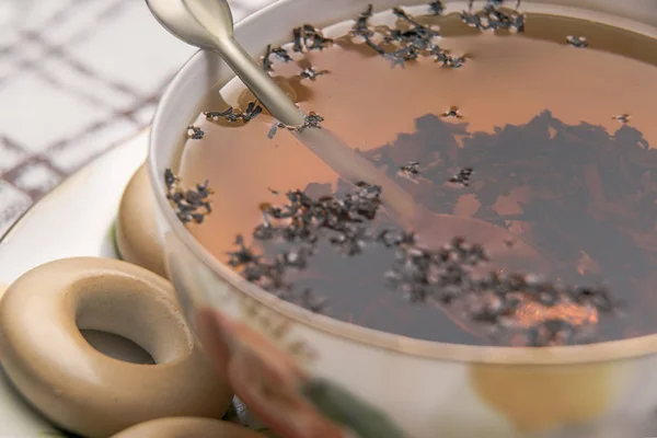 Çay bardağı kaşık ile yakın çekim, fincan çay ve simit üzerinde damalı masa örtüsü