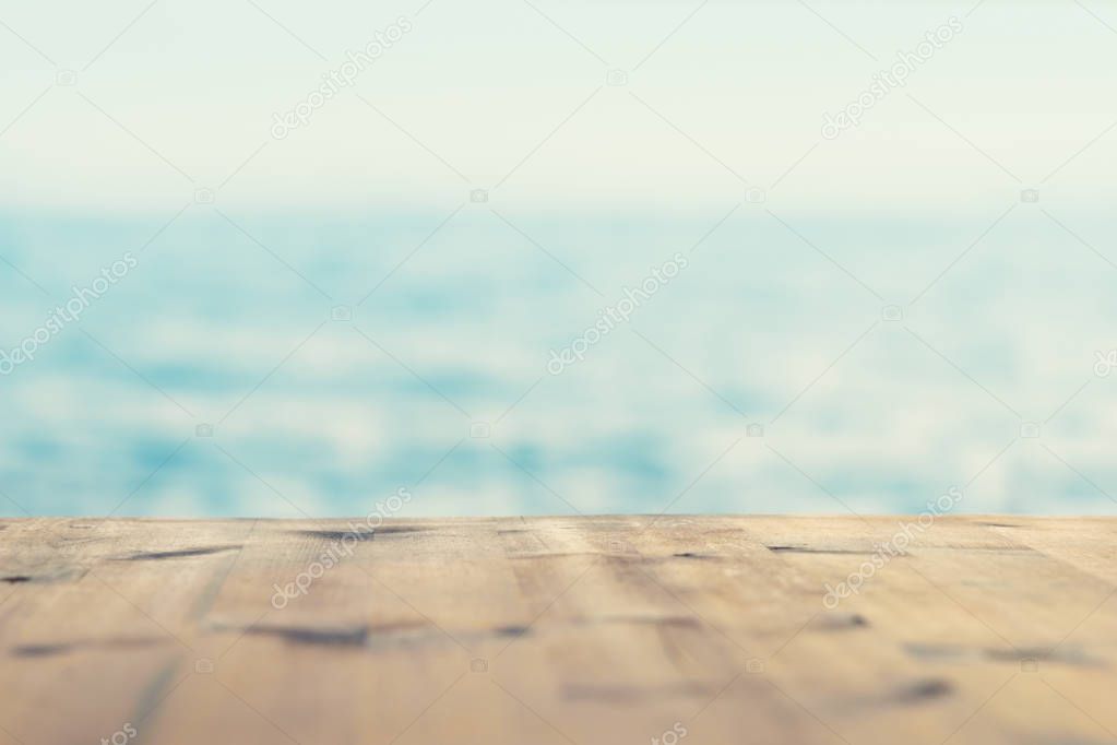 Summer background of empty wooden table in background of sea and sky in soft focus