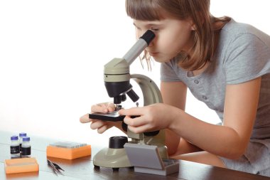 Genç kız okul laboratuvar. Mikroskopla çalışan araştırmacı