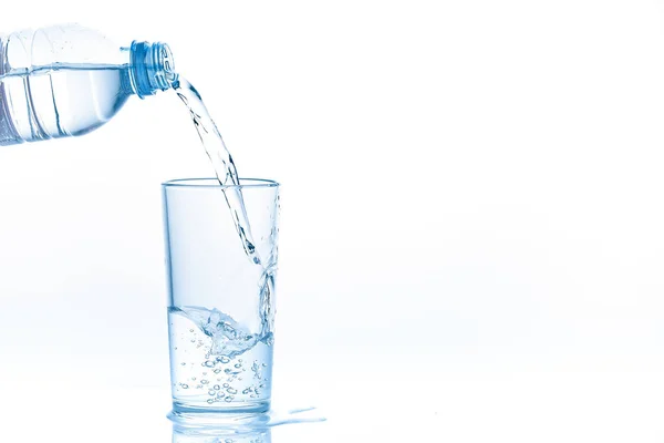 Gießen von Wasser aus der Flasche in Glas auf weißem Hintergrund. Foto mit Kopierraum. — Stockfoto