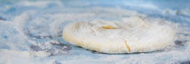 Masaya un serpiştirilmiş hamur serpiştirildi. Hamur pişirme hazırlığı.