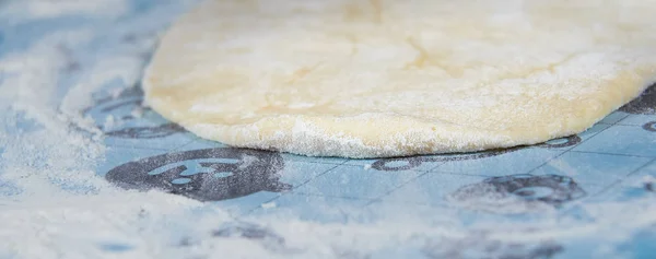 La masa extendida espolvoreada con harina sobre la mesa. Preparación de masa para hornear pasteles . — Foto de Stock