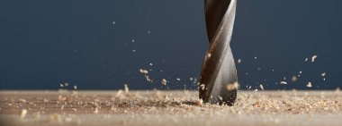 Ahşap matkabın ucu bulanık ve gri arka planda tıraş oluyor. Fotoğraf alanı kopyala.