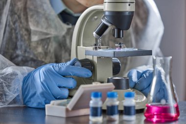 Eczacılık laboratuvarında mikroskopla çalışan bilim adamı ve kimyagerin yatay görüntüsü..