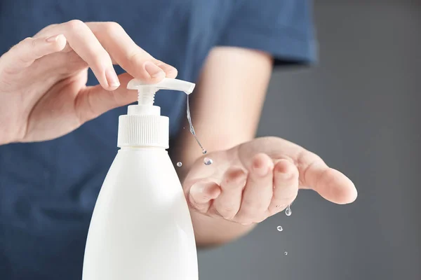 Female hands using hand sanitizer gel pump dispenser. Drops of gel close-up.