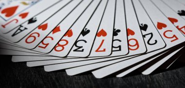 Horizontal shot of playing cards fanned out on a black background. The concept of the game. clipart