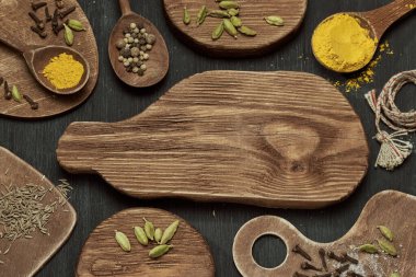 Ahşap kesme tahtalarında farklı şekillerde koyu arkaplanda baharatların yatay görüntüsü.