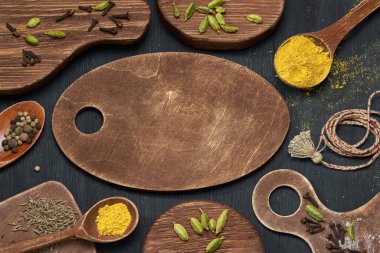 Ahşap kesme tahtalarında farklı şekillerde koyu arkaplanda baharatların yatay görüntüsü.