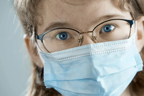 Portrét mladé dívky v brýlích a lékařská maska zblízka. Epidemie chřipky, alergie na prach, ochrana proti virům. Koronavirová pandemie. — Stock fotografie