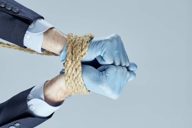 Plastik eldivenli iş adamının yatay görüntüsü gri arka planda bir iple bağlanmış..