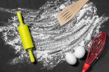 Hamur için malzemeler. Un, yumurta, oklava ve siyah bir çizik arka plan boş tahta. Üstten Görünüm. Düz yatıyordu. Mockup menü veya tarifi.