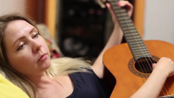 Красивая девушка подстраивает гитару — стоковое видео