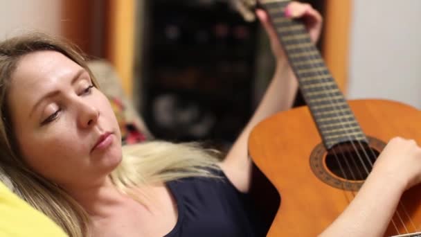 Beautiful girl adjusts guitar — Stock video