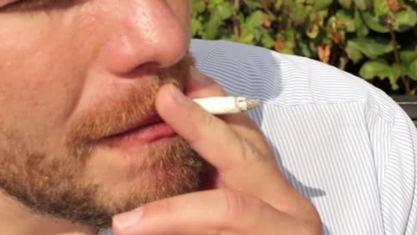 Man smokes on the bench in the park — Stockvideo