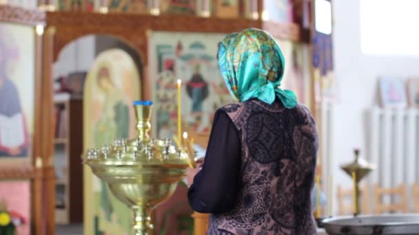 Mujer enciende una vela y reza en la Iglesia Ortodoxa — Vídeos de Stock