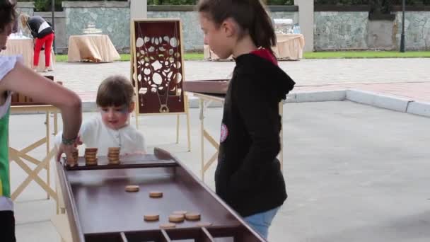 Rusland, Novosibirsk, 25 oktober 2016. Zhakkolo spelende kinderen op het festival, het gooien van houtsnippers in de putten — Stockvideo