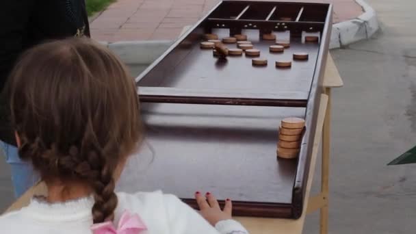 ZHAKKOLO niños jugando en el festival, lanzando astillas de madera en los pozos — Vídeo de stock