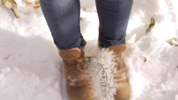Kvinna i bruna skor med glädje sparkar den första snön under fötterna. — Stockvideo