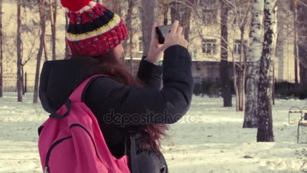 Jovem mulher leva vídeo em seu smartphone no parque de inverno — Vídeo de Stock