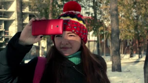 Young woman takes video on your smartphone in the winter park — Stock Video