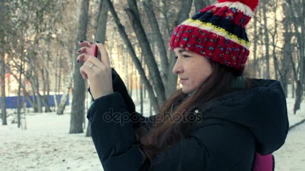 Jovem mulher leva vídeo em seu smartphone no parque de inverno — Vídeo de Stock