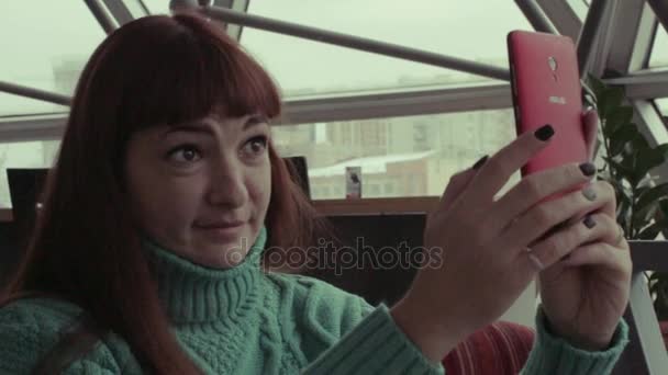 Mujer atractiva tomando fotos en su teléfono inteligente mientras está sentado en un café — Vídeos de Stock