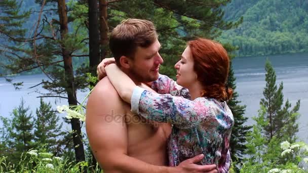 Lyckliga paret på en grön äng vid sjön njuter av skönheten i den omgivande — Stockvideo