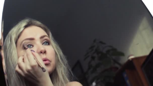 Όμορφη ξανθιά κοπέλα κάνει βραδυνό μακιγιάζ κοντά στον καθρέφτη — Αρχείο Βίντεο